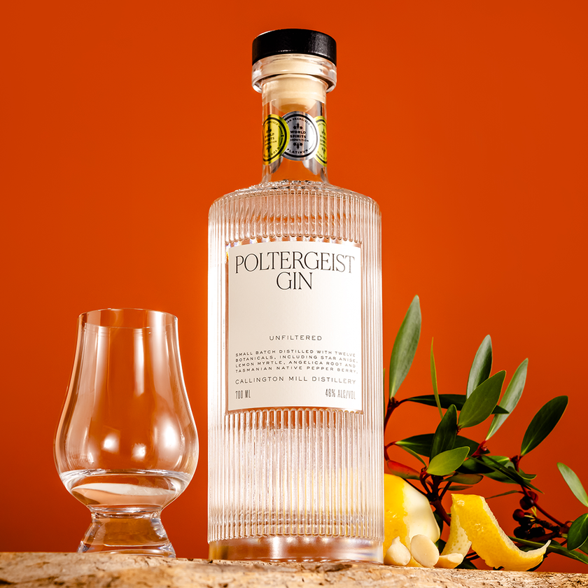 Poltergeist Unfiltered Tasmanian gin bottle with a glass, lemon and olive leaves